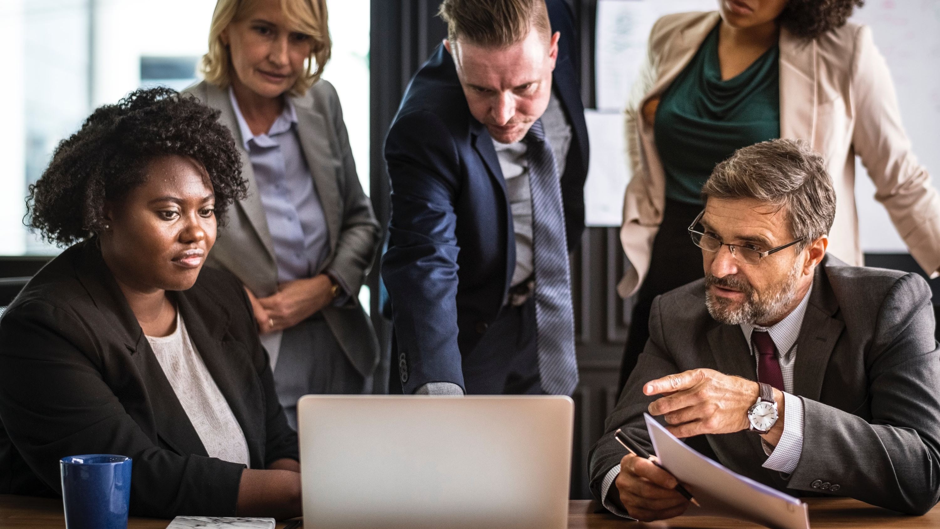 5 employees gathered around a laptop understanding indirect R&D activitites for R&D tax credits