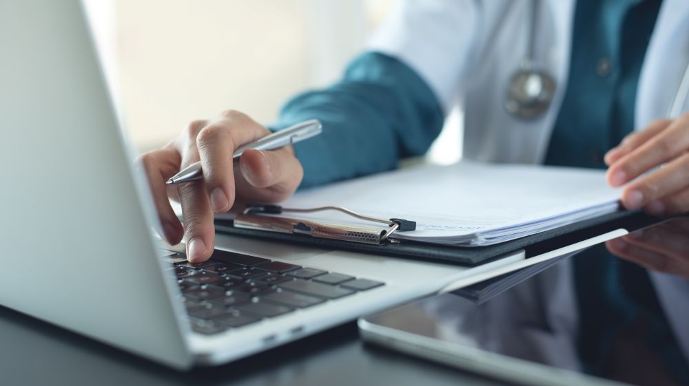 Person Filling Out Report On Laptop
