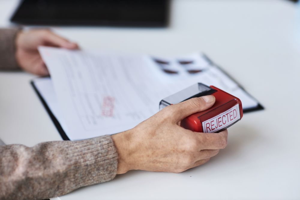Person Stamping Document With Word Rejected
