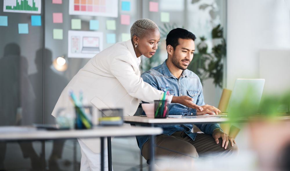 Female Colleague Pointing To Male Colleague's Laptop